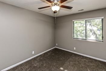 an empty bedroom with a ceiling fan and a window